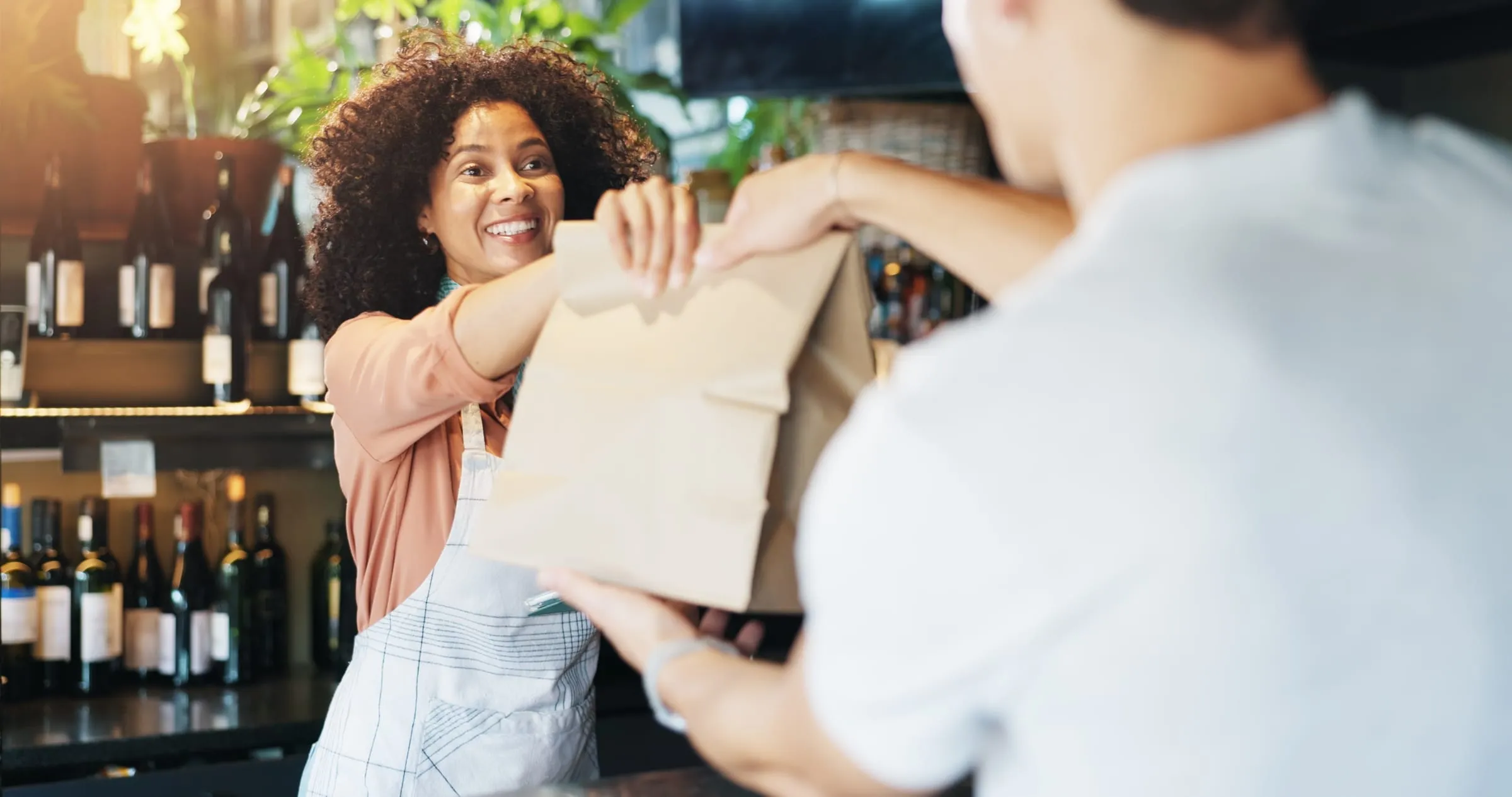 Winkelier geeft een klant een papieren tas aan